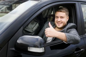 man giving a thumbs up in a car